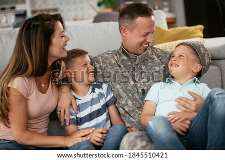 Happy soldier sitting on the floor with his family. Soldier and his wife enjoying at home with children.	