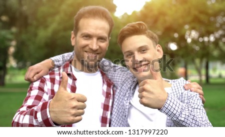 Happy son and father showing thumbs-up, enjoying pastime together, picnic