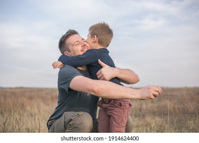 Happy Son Hugging Dad On The  Meadow Background. Concept Of Father-son Relationship