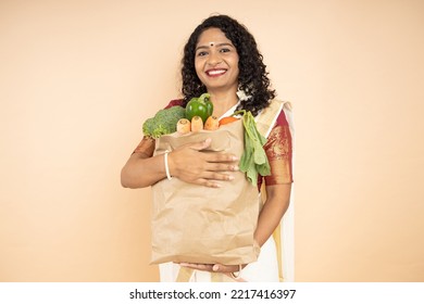 Happy South Indian Woman Hold Grocery Paper Bags With Food Isolated On Beige Background. Studio Shot.