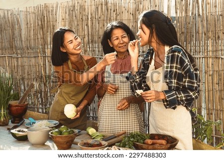 Happy Southeast Asian family having fun preparing Thai food recipe together at house patio
