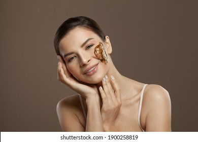Happy spa model woman with scrub on her skin on brown background. Facial treatment, body care and skin care concept
