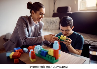 Happy special education teacher and man with down syndrome playing with toy blocks during home visit.  - Shutterstock ID 2139861083