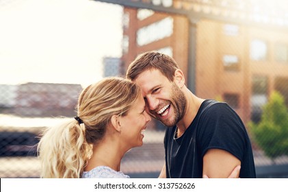 Happy spontaneous attractive young couple share a good joke laughing uproariously and hugging each other outdoors in an urban environment - Shutterstock ID 313752626
