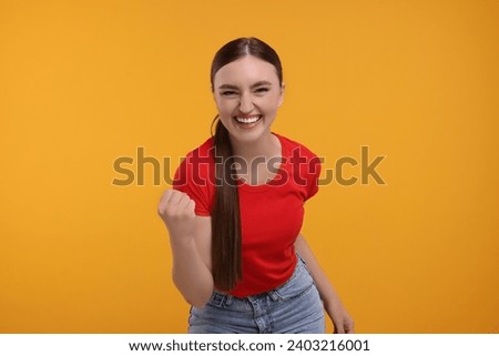 Happy sports fan celebrating on orange background