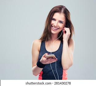 Happy sports woman with smartphone over gray background. Listening music in headphones - Powered by Shutterstock