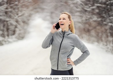 Happy Sportswoman In Shape Standing In Nature At Snowy Winter Day And Having Phone Call. Telecommunications, Winter Fitness, Technology