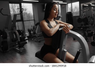 Happy sporty attractive woman smiles and looking at her sport bracelet, checks the time after an intense workout. Female taking a break after exercise and workout. Health care and fitness concept - Shutterstock ID 1841290918