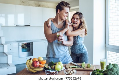 Happy sporty couple is preparing healthy food on light kitchen. Healthy food concept. - Powered by Shutterstock