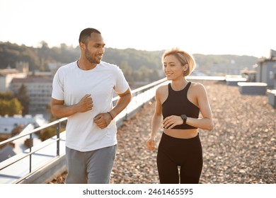 Happy sporty couple promotes healthy lifestyle. Young strong female and male athletes engaged in sports running against background of morning city. - Powered by Shutterstock