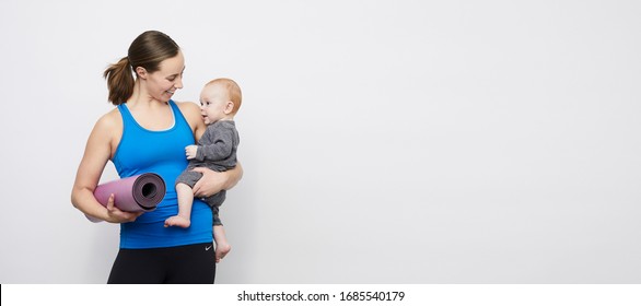 Happy Sporty Mom Looking At Her Kid On A Plain Background With Copy Space 