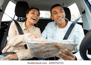 Happy spouses sitting in car holding road map and looking through window. Auto tourism and navigation concept - Powered by Shutterstock