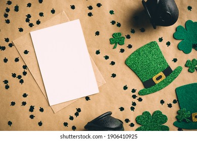 Happy St Patrick’s Day Concept. Flat Lay Composition With Blank Greeting Card Mockup, Irish Elf Hats, Pots Of Gold, Shamrock Clover Leaves On Craft Paper. Vintage, Retro Style.