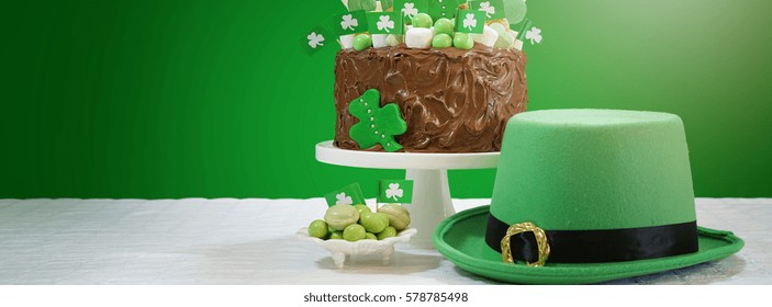 Happy St Patricks Day green and white party table with showstopper chocolate cake decorated with candy, cookies and shamrock flags, sized to fit a popular social media cover image placeholder. - Powered by Shutterstock