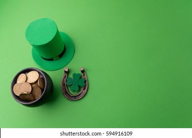 Happy St Patricks Day leprechaun hat with gold coins and lucky charms on green background. Top view. - Powered by Shutterstock