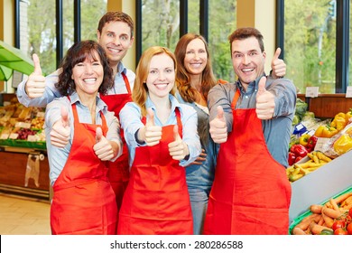 Happy Staff Team In A Supermarket Holding Their Thumbs Up