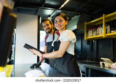 Happy stall vendor and cook smiling while checking the orders of the delivery app on the food truck - Powered by Shutterstock