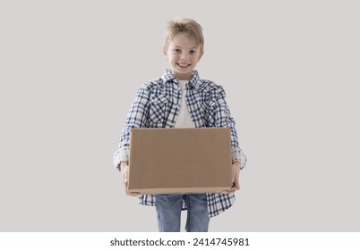 Happy strong boy holding a big cardboard box, delivery and home relocation concept - Powered by Shutterstock