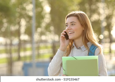 Happy Student Girl Walking And Calling On Mobile Phone  Outdoors With A Green Background