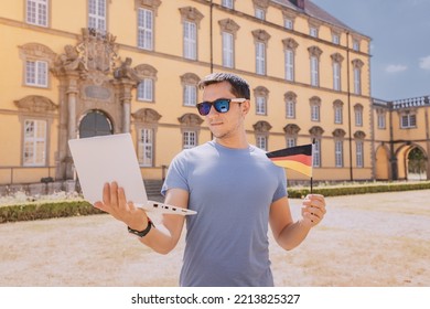 Happy Student Man Near The University Campus With A German Flag And Learning The Language Via The Internet On A Laptop