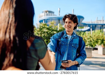 Happy student smiling while shaking hand with a person on campus