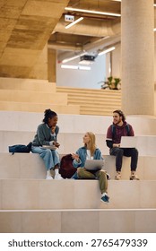 Happy student using laptop while talking to her friends at the university. Copy space.