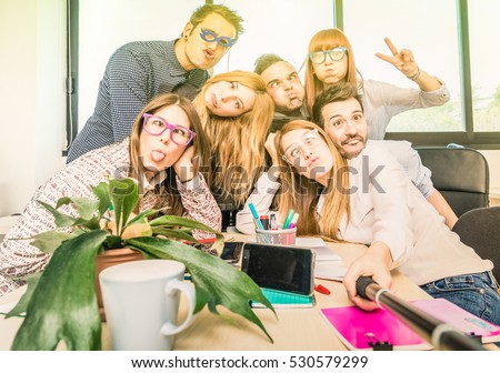 Happy students employee workers group taking selfie with stick - University concept of human resource on working fun time - Startupper at college office - Bright contrasted filter with sunshine halo