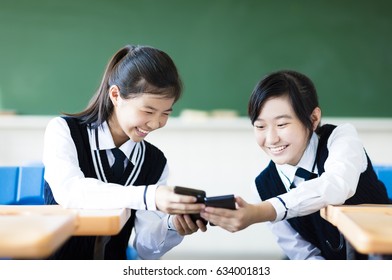 happy students girls watching the smart phone in classroom