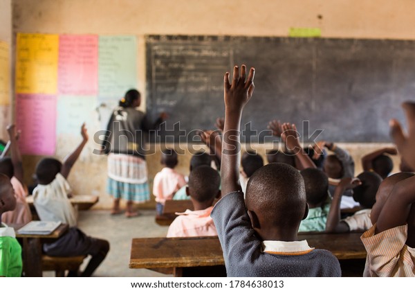 Happy students at a school in Uganda, Africa. \
Students raising their\
hands.