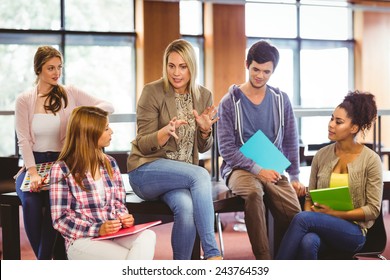 Happy students talking with their teacher in the library - Powered by Shutterstock