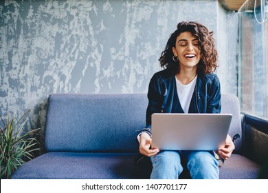 Happy stylish female blogger laughing while chatting with friends in social networks on laptop device using wireless internet in coworking.Positive young woman doing shopping online on website - Powered by Shutterstock