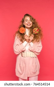 happy stylish girl standing with two lollipops and looking at camera isolated on red - Shutterstock ID 764514514