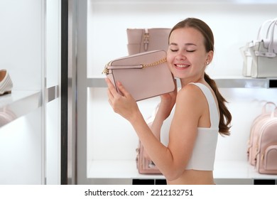 Happy Stylish Girl, Young Teen Teenager Beautiful Woman Is Smiling, Holding New Bag, Handbag, Wants To Buy A Purse In Hands With Eyes Closed In Mall Inside Shop, Store Or Boutique, Shopping