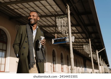 Happy stylish man with reusable cup waiting for the train - Powered by Shutterstock