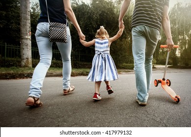 Happy Stylish Parents Holding Hands With Daughter And Walking In Sunny  Street, Amazing Family Moment. Father's Mother's Day