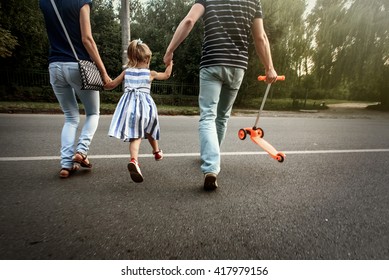 happy stylish parents holding hands with daughter and walking in sunny  street, tender family moment - Powered by Shutterstock