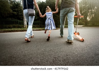 Happy Stylish Parents Holding Hands With Daughter And Walking In Sunny  Street, Amazing Family Moment