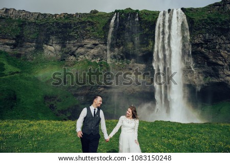 Happy stylish smiling couple walking and kissing in Iceland , on their wedding day.