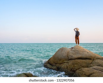 Happy stylische Frau Hipster, die Fotokamera und Lächeln an der sonnigen Küste nahe Wasser, Mädchen tragen Hut und Pullover Reisen allein auf dem Meer.