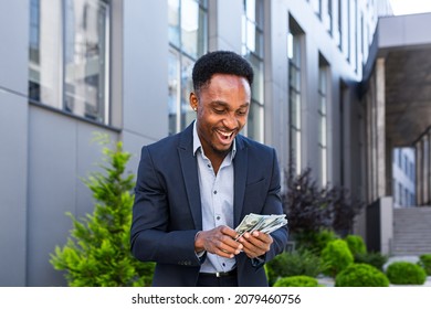 Happy successful African American businessman counts, waves, throws, show off, flaunt, cash money background a modern office building looking at camera Celebrate Winner success in betting stock market