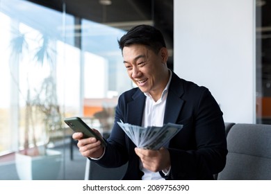 Happy successful asian businessman counts, waves, throws, money in office looking at camera Winner success in betting stock market celebrating victory Indoor business man, worker employee entrepreneur