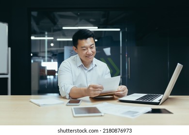 Happy and successful asian businessman reading financial document letter, boss working with documents in office, paperwork