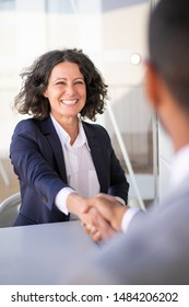 Happy successful business colleagues meeting outside and closing deal. Joyful business woman and man sitting at table, talking and shaking hands. Closing deal concept