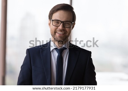 Happy successful business leader in glasses and formal suit head shot portrait. Confident millennial businessman, CEO, company owner, director looking at camera, smiling, laughing
