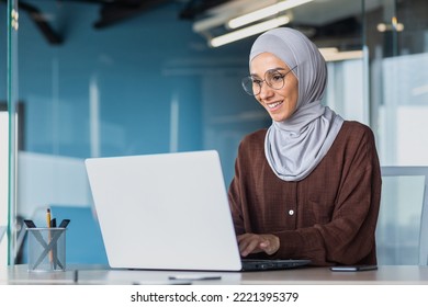 Happy and successful business woman in hijab working with laptop inside modern office building, muslim woman in glasses smiling and happy with work achievement. - Powered by Shutterstock