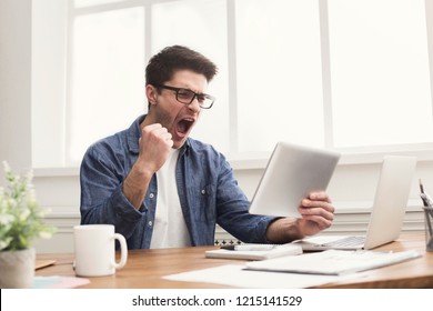 Happy successful businessman with digital tablet win, celebrate in office, sitting at workplace. Man in eye glasses, job in internet. - Shutterstock ID 1215141529