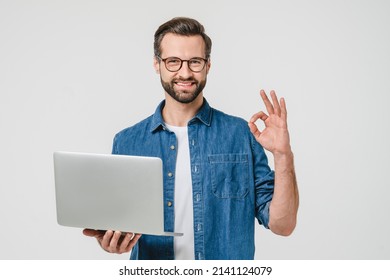 Feliz y exitoso estudiante caucásico, estudiante independiente, que muestra un gesto correcto, que usa laptop para estudios remotos, e-learning, que trabaja a distancia aislado en fondo blanco