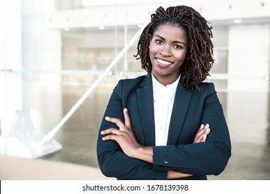 Happy Successful Professional Posing Near Office Building. Young African American Business Woman With Arms Folded Standing Outside, Looking At Camera, Smiling. Female Business Leader Concept