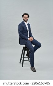 Happy successful rich young indian business man ceo leader, wealthy arab professional manager, confident male businessman executive wearing suit sitting on chair isolated on beige, vertical portrait. - Shutterstock ID 2206163785