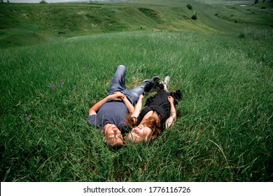 Happy summer couple on vacation. Lovers lie on the grass.
Happy guy and girl. Beautiful girl with long dark hair
and a young guy. Happy couple concept. Environment concept, nature
